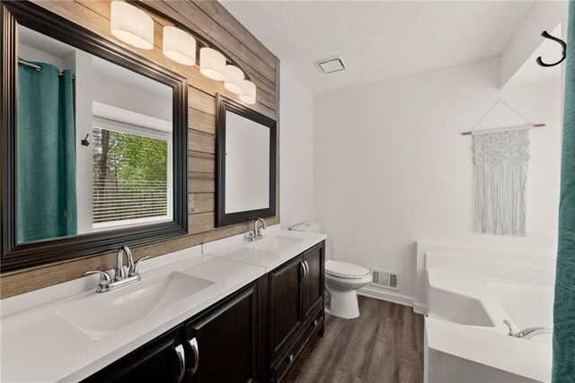 full bathroom with wood finished floors, a sink, visible vents, and a washtub