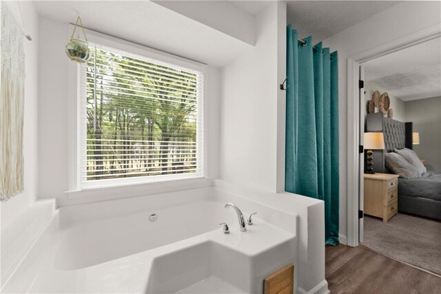 full bath with a bath, wood finished floors, and a healthy amount of sunlight