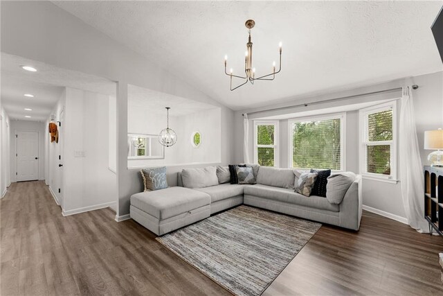 living room featuring baseboards, vaulted ceiling, an inviting chandelier, recessed lighting, and wood finished floors