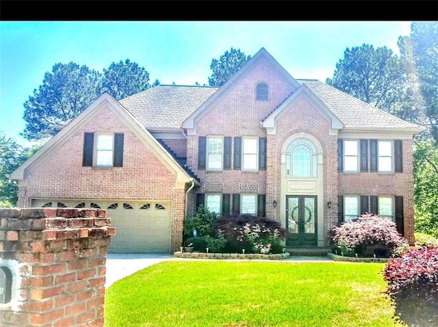 colonial house with concrete driveway, an attached garage, french doors, brick siding, and a front yard