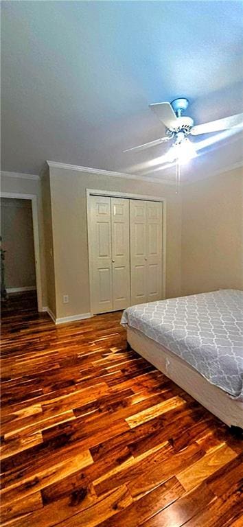 bedroom featuring a ceiling fan, crown molding, hardwood / wood-style floors, a closet, and baseboards