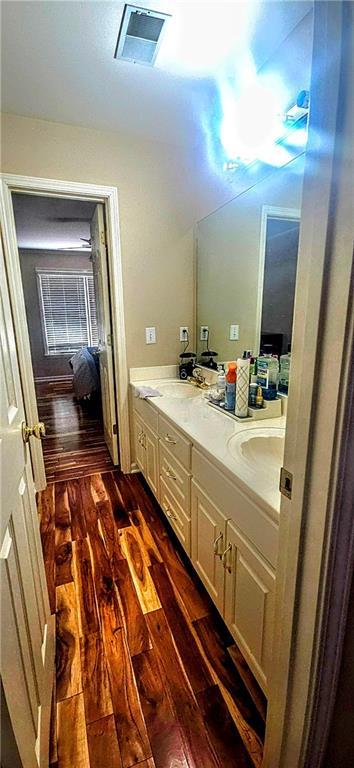 bathroom with double vanity, wood finished floors, visible vents, and a sink