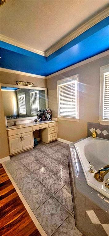 bathroom with vanity, ornamental molding, a bath, a wealth of natural light, and baseboards