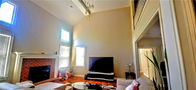 living area featuring baseboards, wood finished floors, a brick fireplace, and high vaulted ceiling