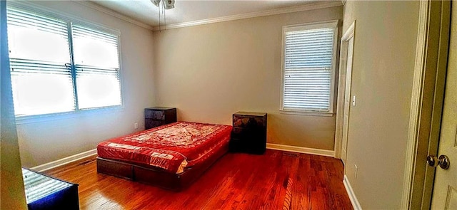 bedroom with wood finished floors, baseboards, and crown molding