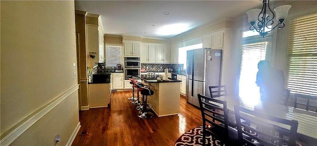 kitchen featuring a center island, dark wood-style flooring, dark countertops, a notable chandelier, and appliances with stainless steel finishes