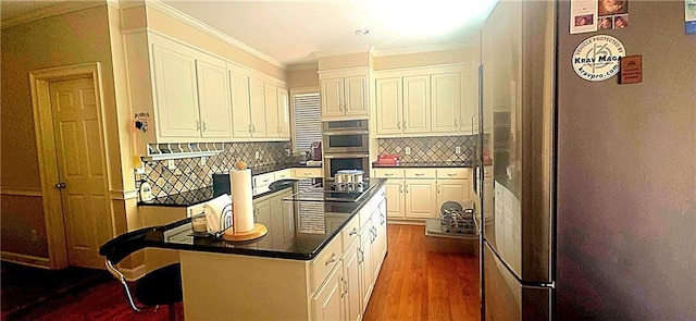 kitchen with white cabinets, dark countertops, ornamental molding, appliances with stainless steel finishes, and dark wood-style flooring