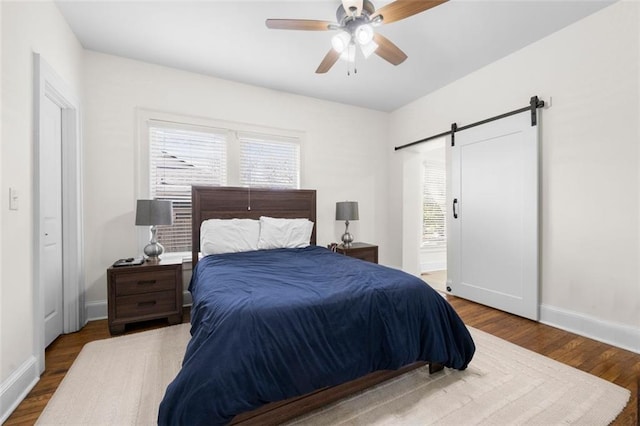 bedroom with hardwood / wood-style flooring, a barn door, and ceiling fan