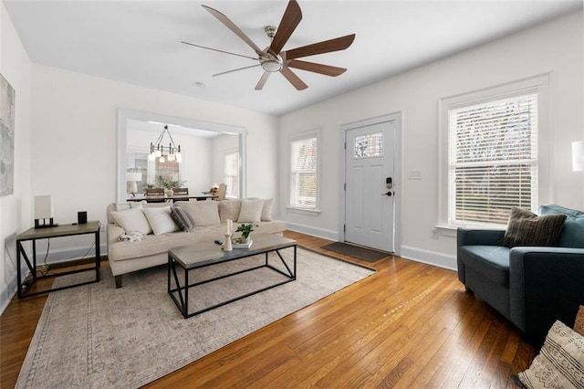 living room featuring ceiling fan with notable chandelier and hardwood / wood-style floors