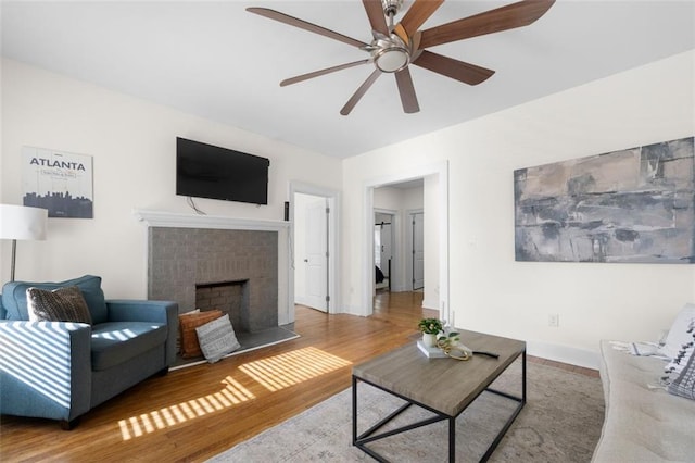 living room with a brick fireplace, hardwood / wood-style floors, and ceiling fan