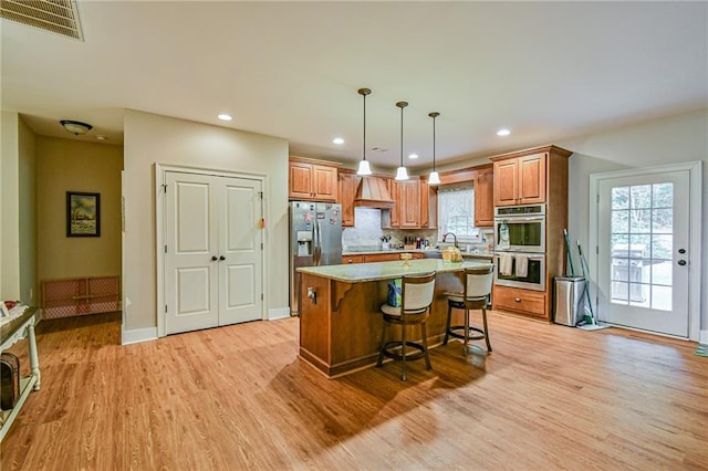 kitchen featuring hanging light fixtures, a kitchen breakfast bar, light hardwood / wood-style floors, a kitchen island, and appliances with stainless steel finishes