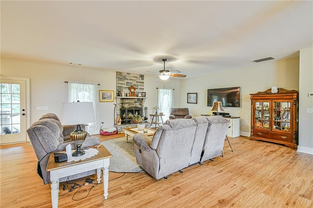 living room with ceiling fan, light wood-type flooring, and a fireplace