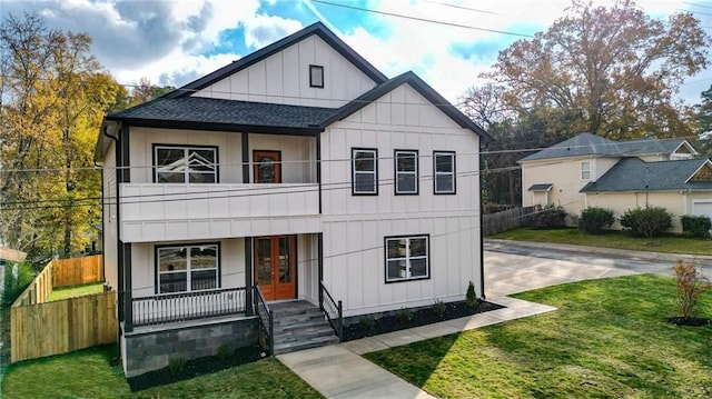 view of front of property with covered porch, a balcony, french doors, and a front lawn