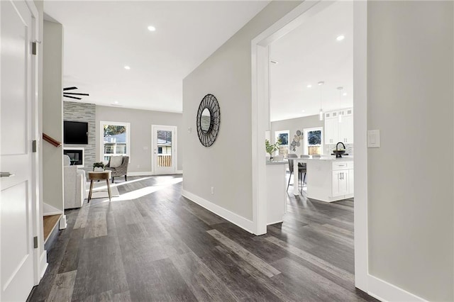 corridor with a wealth of natural light, sink, and dark wood-type flooring