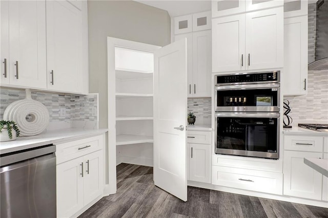 kitchen with decorative backsplash, stainless steel appliances, exhaust hood, white cabinets, and dark hardwood / wood-style floors