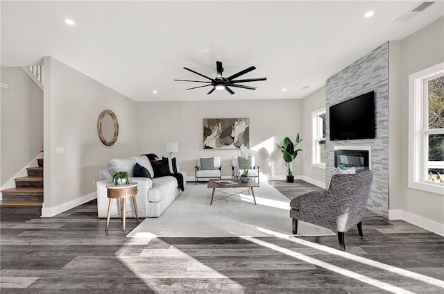 living room featuring a fireplace, dark wood-type flooring, and a healthy amount of sunlight