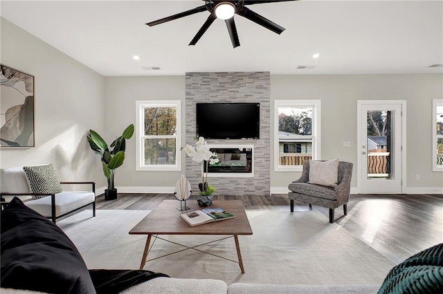 living room with a tile fireplace, wood-type flooring, and ceiling fan