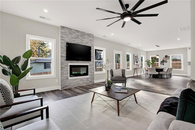 living room with ceiling fan, a large fireplace, and dark hardwood / wood-style floors