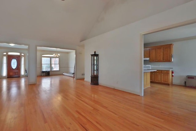 unfurnished living room featuring light hardwood / wood-style floors, a notable chandelier, and high vaulted ceiling