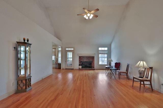 living room with high vaulted ceiling, a fireplace, ceiling fan, and light hardwood / wood-style floors