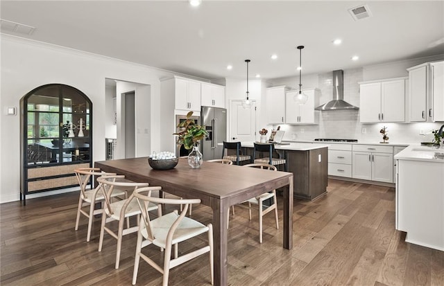 kitchen with a center island, decorative light fixtures, wall chimney range hood, white cabinetry, and high quality fridge