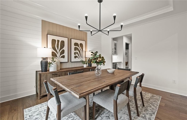 dining room with wood walls, a notable chandelier, crown molding, and dark hardwood / wood-style floors