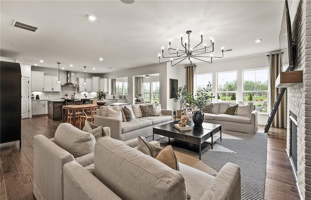 living room featuring a brick fireplace, an inviting chandelier, and dark hardwood / wood-style floors