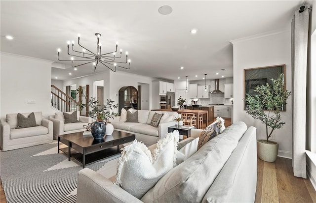 living room with an inviting chandelier, ornamental molding, and light hardwood / wood-style flooring