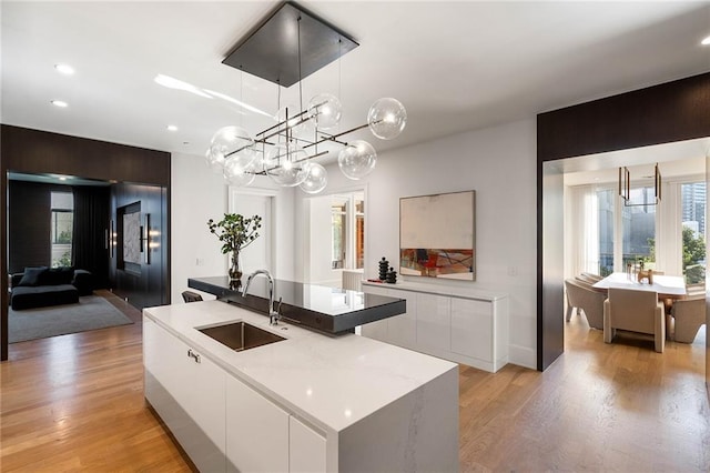 kitchen with white cabinets, pendant lighting, sink, and an island with sink