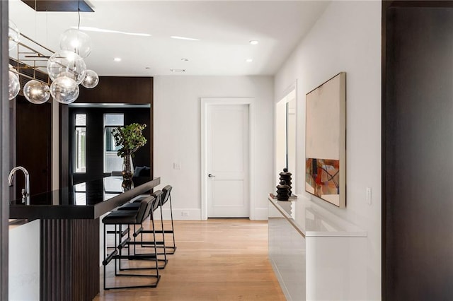 interior space featuring a breakfast bar, dark brown cabinetry, light hardwood / wood-style flooring, and sink