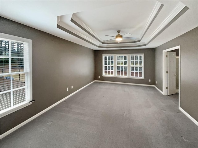 unfurnished room with ornamental molding, a tray ceiling, ceiling fan, and baseboards