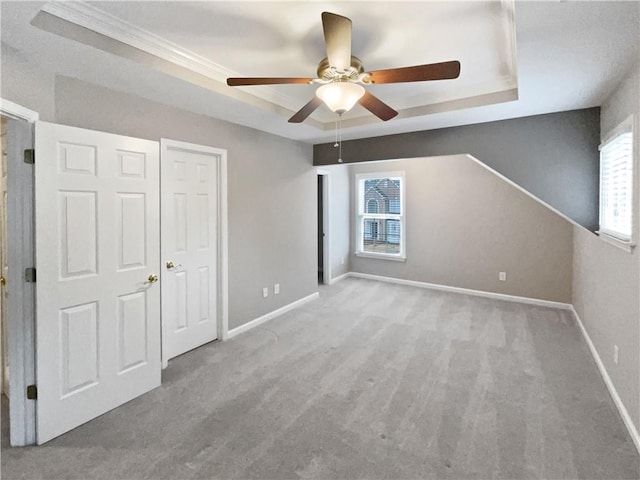 unfurnished bedroom featuring ceiling fan, baseboards, a raised ceiling, and carpet flooring