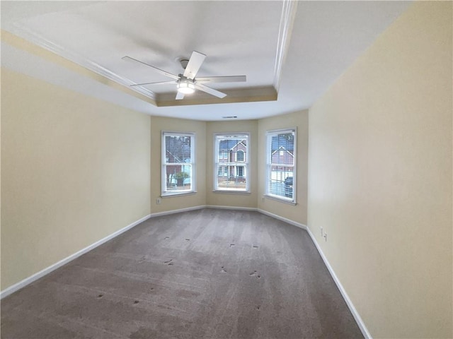 unfurnished room with ornamental molding, ceiling fan, a tray ceiling, and baseboards