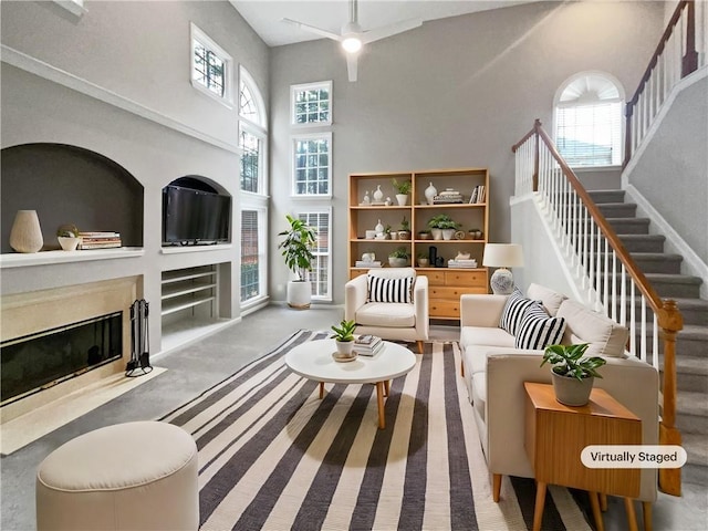 sitting room with a wealth of natural light, a high end fireplace, a towering ceiling, and stairs