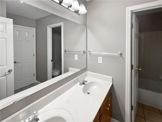 full bath featuring double vanity, a sink, toilet, and tile patterned floors