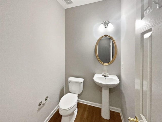 half bath featuring visible vents, wood finished floors, toilet, and baseboards