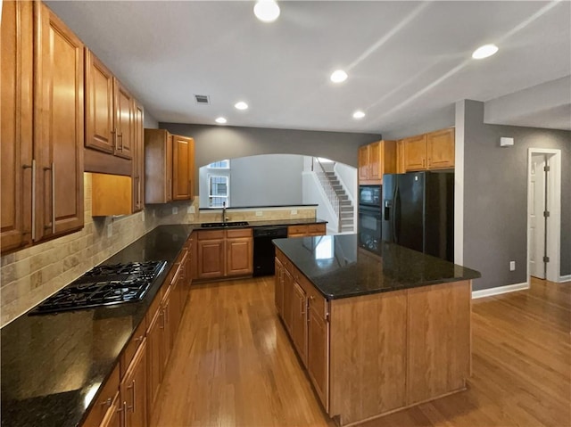 kitchen with black appliances, tasteful backsplash, visible vents, and light wood-style floors