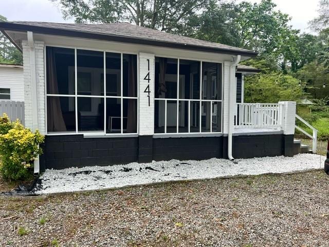 view of side of property featuring a shingled roof and a sunroom