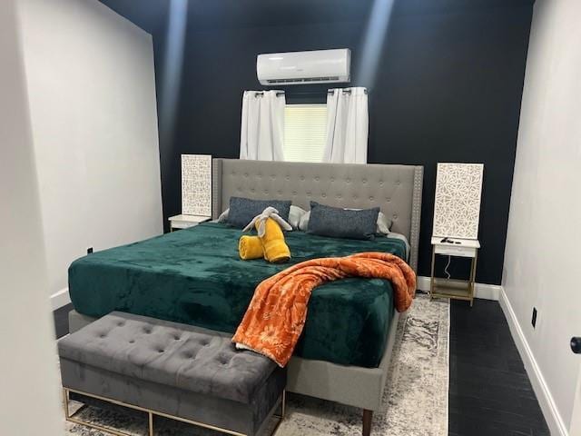 bedroom featuring a wall mounted AC, wood finished floors, and baseboards