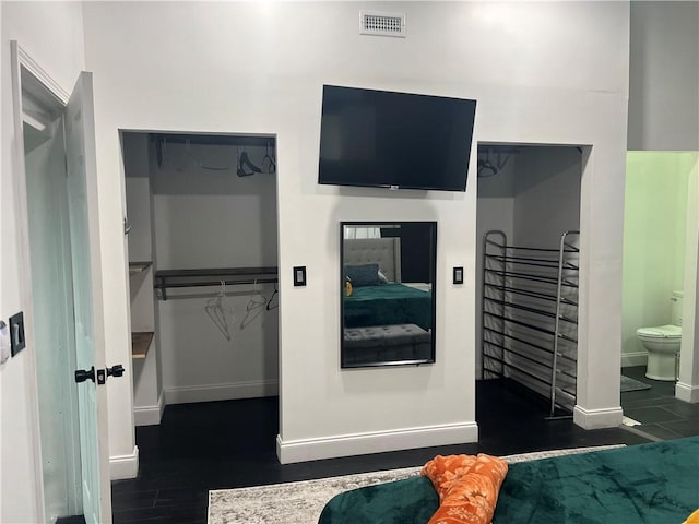 interior space with baseboards, visible vents, wood finished floors, a spacious closet, and a closet