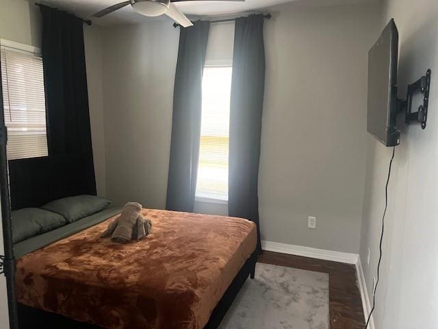 bedroom with ceiling fan, wood finished floors, and baseboards