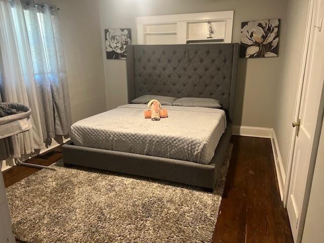 bedroom with dark wood finished floors and baseboards