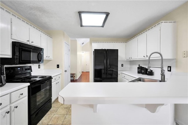 kitchen with a breakfast bar, a peninsula, black appliances, and a sink