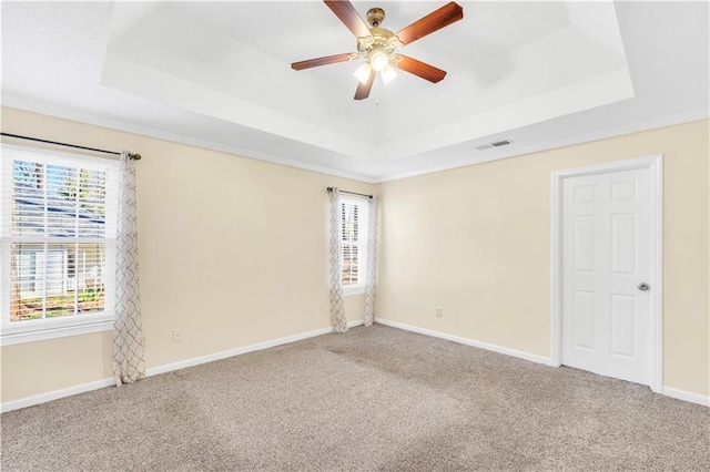 empty room featuring a raised ceiling, carpet flooring, and visible vents