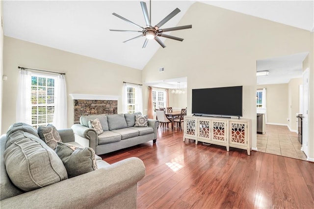 living room with ceiling fan, wood finished floors, visible vents, and high vaulted ceiling