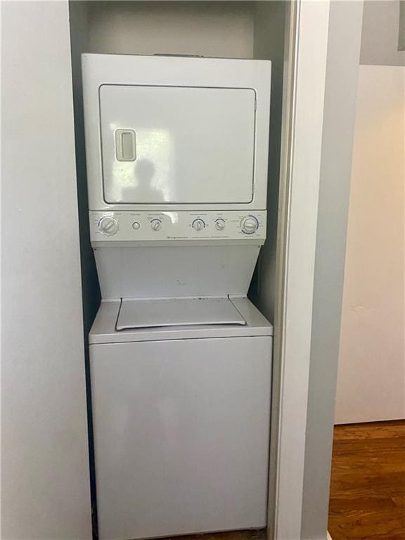 clothes washing area featuring hardwood / wood-style flooring and stacked washer and clothes dryer