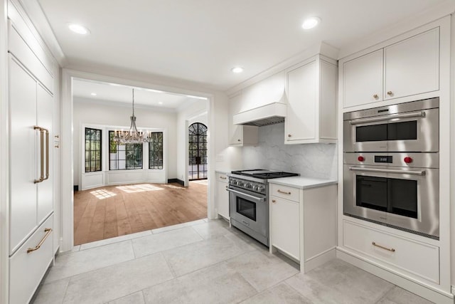 650 Moores Mill Rd NW Unit 1, Atlanta, GA 30327 - kitchen featuring appliances with stainless steel finishes, a chandelier, decorative backsplash, light countertops, and ornamental molding