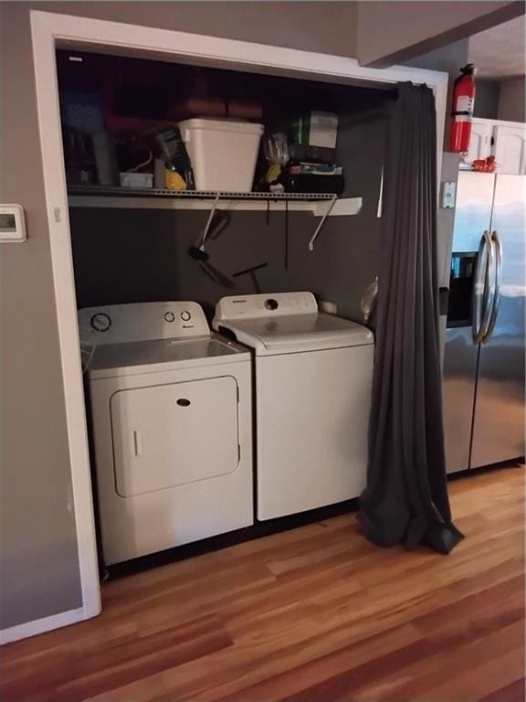 laundry area with light hardwood / wood-style flooring and washing machine and dryer