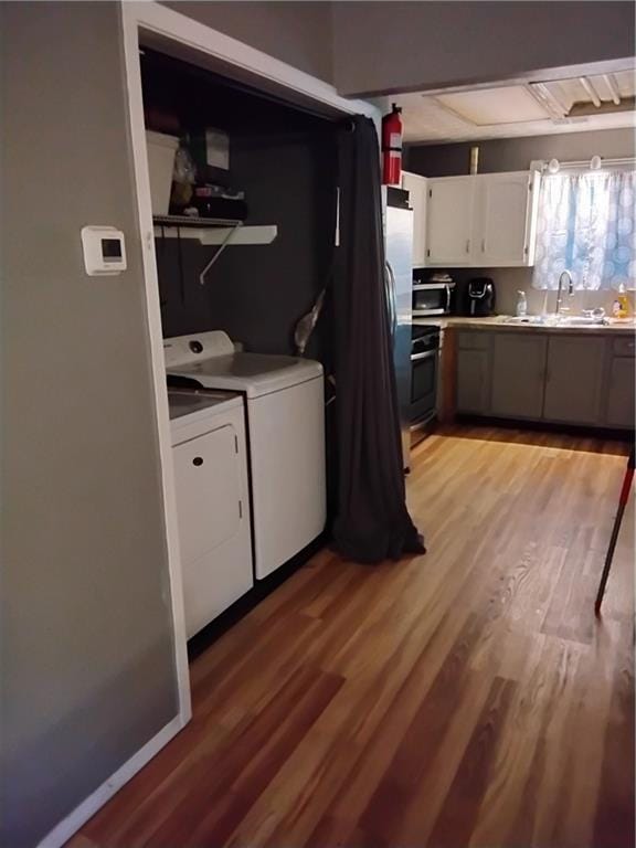 laundry area featuring washing machine and clothes dryer, sink, and light hardwood / wood-style floors