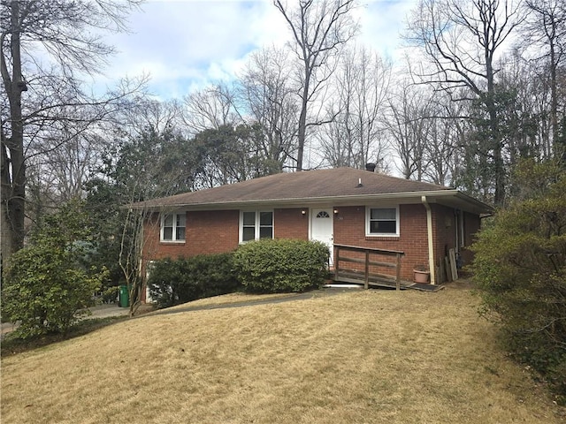 view of front of home featuring brick siding, a chimney, and a front yard